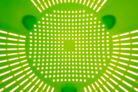 Close-up of a green plastic colander, a kitchen utensil to drain pasta, on a white background