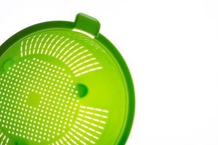 Close-up of a green plastic colander, a kitchen utensil to drain pasta, on a white background. Photo with copy space.の写真素材