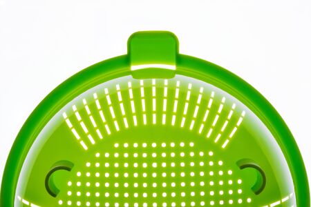 Close-up of a green plastic colander, a kitchen utensil to drain pasta, on a white background. Photo with copy space.の写真素材