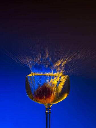 Strawberry thrown into a glass filled with liquid or alcohol and splashing. On a dark blue background.の写真素材