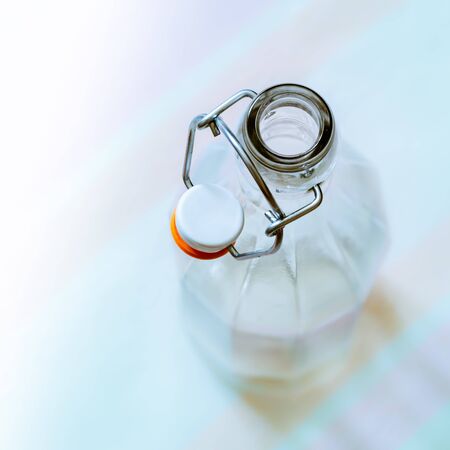 Top view of a glass bottle with a  wire bail clasp ceramic stopper on a blue, pink and orange stripped tableclothの写真素材