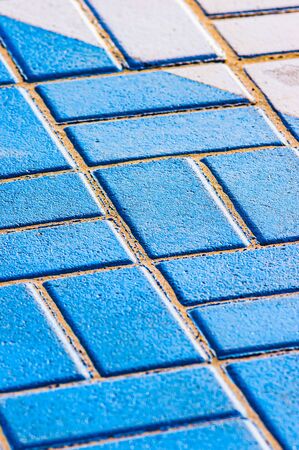 Texture of blue brick tiles and yellow sand with copy space, to be used as background. Selective...