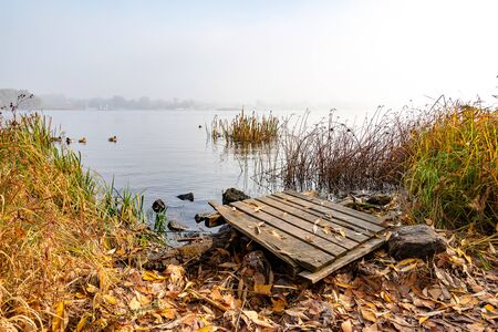 A wooden pontoon over big stones close to the blue Dnieper river is waiting for the fisherman.の写真素材