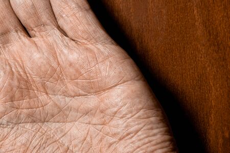Picture of elderly male hands on a wooden background. Detail of the palm of the hand.の写真素材