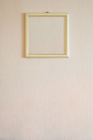 A true modern photo frame with gold ornaments and blank copy space, for the insertion of any image, on a wall covered with beige painted wallpaper.の写真素材