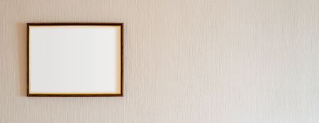 A true antique wooden photo frame with gold ornaments and blank copy space, for insertion of any image, on a wall covered by beige painted wallpaper.の写真素材