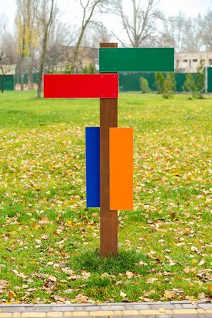 Blank directional arrow signs in the park, with a green grass background covered by autumn leavesの写真素材