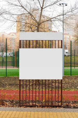 Blank white information board in the park in autumn. Naked trees and autumn leaves on the groundの写真素材