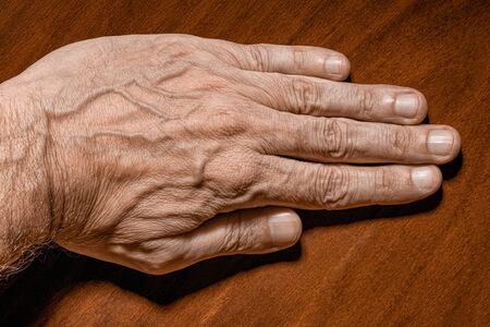 Color photo of a senior man left hand on a wooden backgroundの写真素材