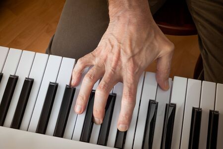 Close up detail on the hand of a musician playing the black and white keys of an electronic  music keyboard.の写真素材