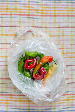 Hot red chili peppers in a translucide cellophane bag, put on an orange, red  and blue stripped napkinの写真素材