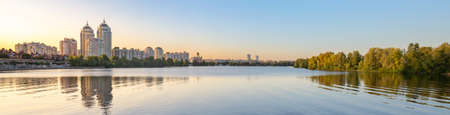 Panoramic view oth the high Obolon buildings near the Dnieper river in Kiev, Ukraine. Blue clear sky and reflection in the water.の写真素材