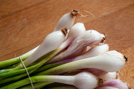 A bunch of little white and pink onions, cebollitas, on a wooden cuttingboardの写真素材