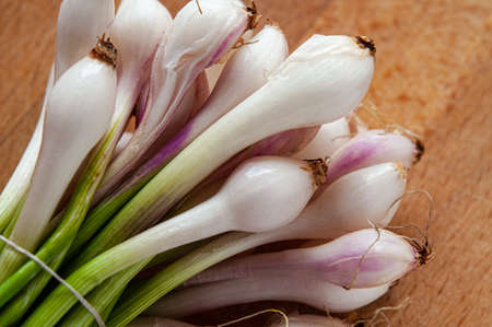 A bunch of little white and pink onions, cebollitas, on a wooden cuttingboardの写真素材