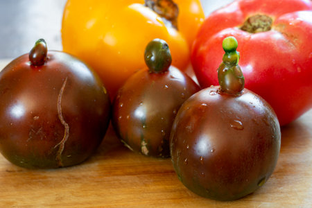 Various kind of tomatoes, yellow, red and black, on a cutting boardの写真素材