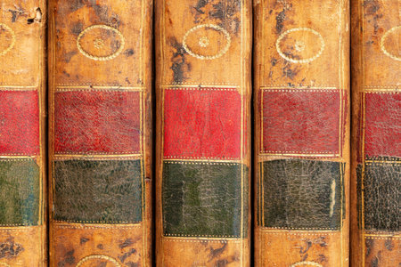 Pile of antique books with a leather cover and golden ornaments on a wooden tableの写真素材
