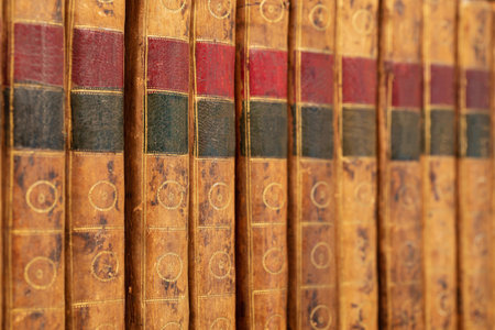 Pile of antique books with a leather cover and golden ornaments on a wooden tableの写真素材