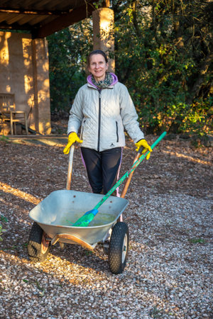 Woman gardening, moving an empty wheelbarrow to collect fallen leaves in early winter, in Provence, a region of southern France.の写真素材