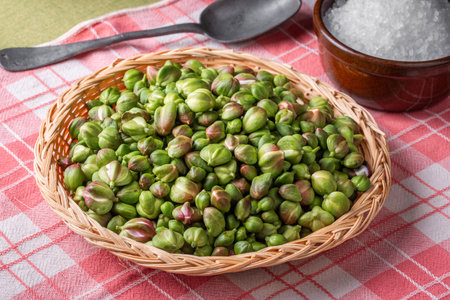 Caper buds in a basket and big sea salt on a table. Ready to be prepared for seasoning and picklesの写真素材