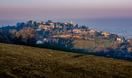 View of the medieval village of Montegridolfo, from the road from Belvedere Fogliense to Mondaino, before sunset.の写真素材