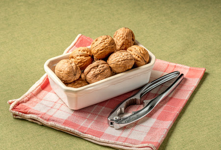 Heap of dry walnuts in a cup, with a nutcracker
