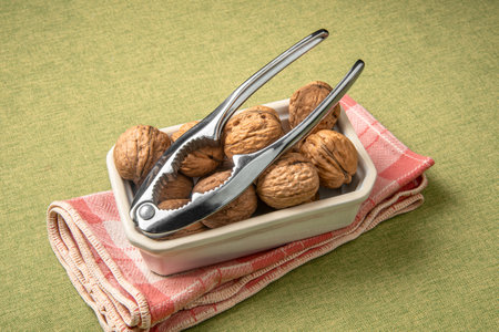Heap of dry walnuts in a cup, with an iron nutcrackerの写真素材