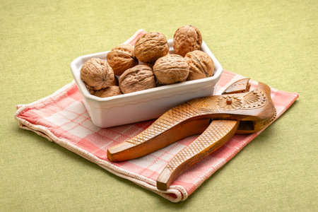 Heap of dry walnuts in a cup, with a wooden nutcrackerの写真素材