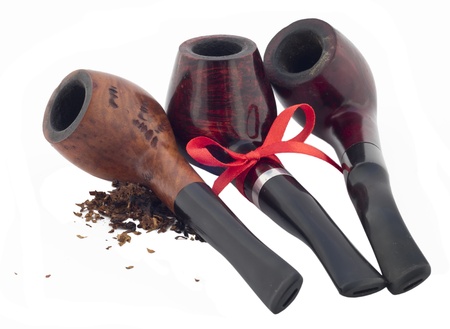 Three wooden pipes with scattered tobacco and with a red ribbon.