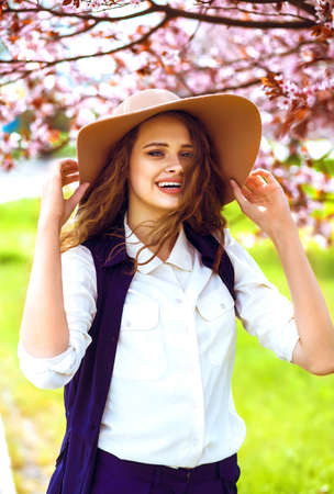 Outdoor portrait of young beautiful fashionable lady posing near flowering tree.の写真素材