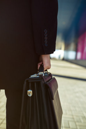 leather briefcase in his hand. young businessman walking on the streetの写真素材