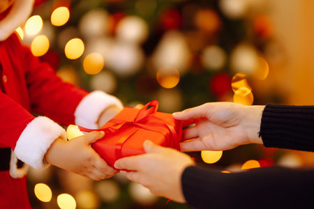 Christmas gift in the hands of a child. Cute little boy receiving christmas present from parent.の写真素材
