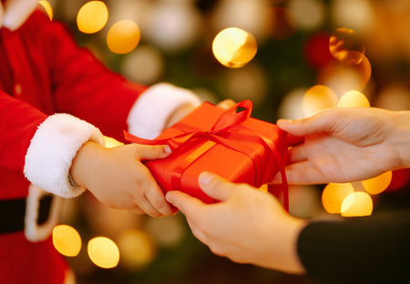 Christmas gift in the hands of a child. Cute little boy receiving christmas present from parent.の写真素材