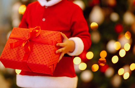 Little boy in santa costume with christmas gift. Happy child holding red present box. new year.の写真素材