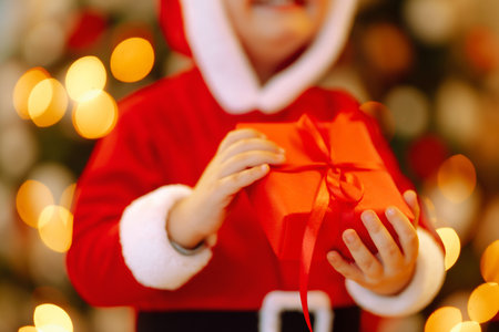 Little boy in santa costume with christmas gift. Happy child holding red present box. new year.の写真素材