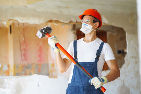 Young male builder in hard hat holding tools. Apartment repair and renovation concept.の写真素材