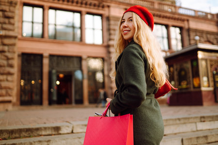 Elegant woman wearing stylish red beret with shopping bags in the city street. Autumn shopping.の写真素材