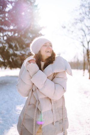 Happy woman in winter style clothes walking in the snowy park. Nature, holidays, travel concept.の写真素材