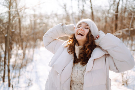 Happy woman in winter style clothes walking in the snowy park. Nature, holidays, travel concept.の写真素材