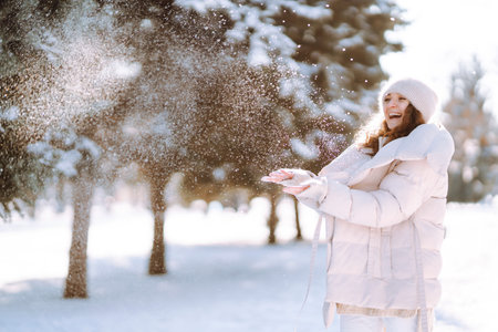 Happy woman in winter style clothes walking in the snowy park. Nature, holidays, travel concept.の写真素材