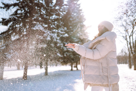 Happy woman in winter style clothes walking in the snowy park. Nature, holidays, travel concept.の写真素材