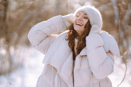 Happy woman in winter style clothes walking in the snowy park. Nature, holidays, travel concept.の写真素材