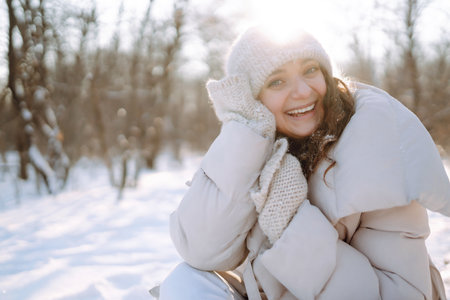 Happy woman in winter style clothes walking in the snowy park. Nature, holidays, travel concept.の写真素材
