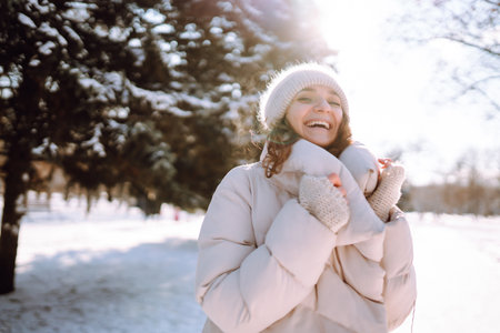 Happy woman in winter style clothes walking in the snowy park. Nature, holidays, travel concept.の写真素材