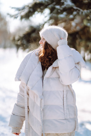 Young woman in winter style clothes walking in the snowy park. Winter fashion, holidays.の写真素材