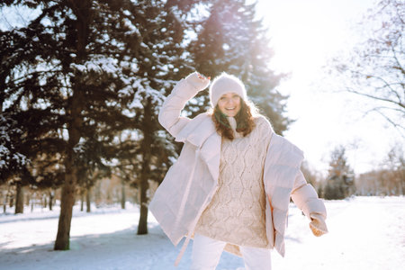 Young woman in winter style clothes walking in the snowy park. Winter fashion, holidays.の写真素材