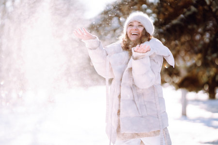 Young woman in winter style clothes walking in the snowy park. Winter fashion, holidays.の写真素材