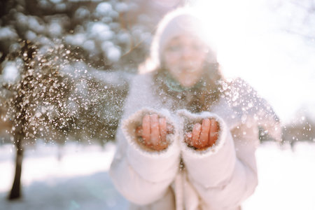 Young woman in winter style clothes walking in the snowy park. Winter fashion, holidays.の写真素材