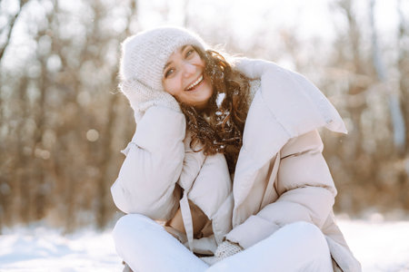 Young woman in winter style clothes walking in the snowy park. Winter fashion, holidays.の写真素材