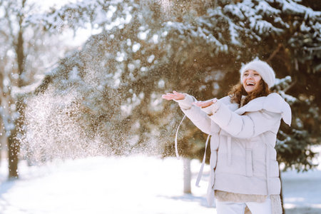 Young woman in winter style clothes walking in the snowy park. Winter fashion, holidays.の写真素材
