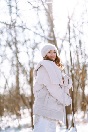 Young woman in winter style clothes walking in the snowy park. Winter fashion, holidays.の写真素材